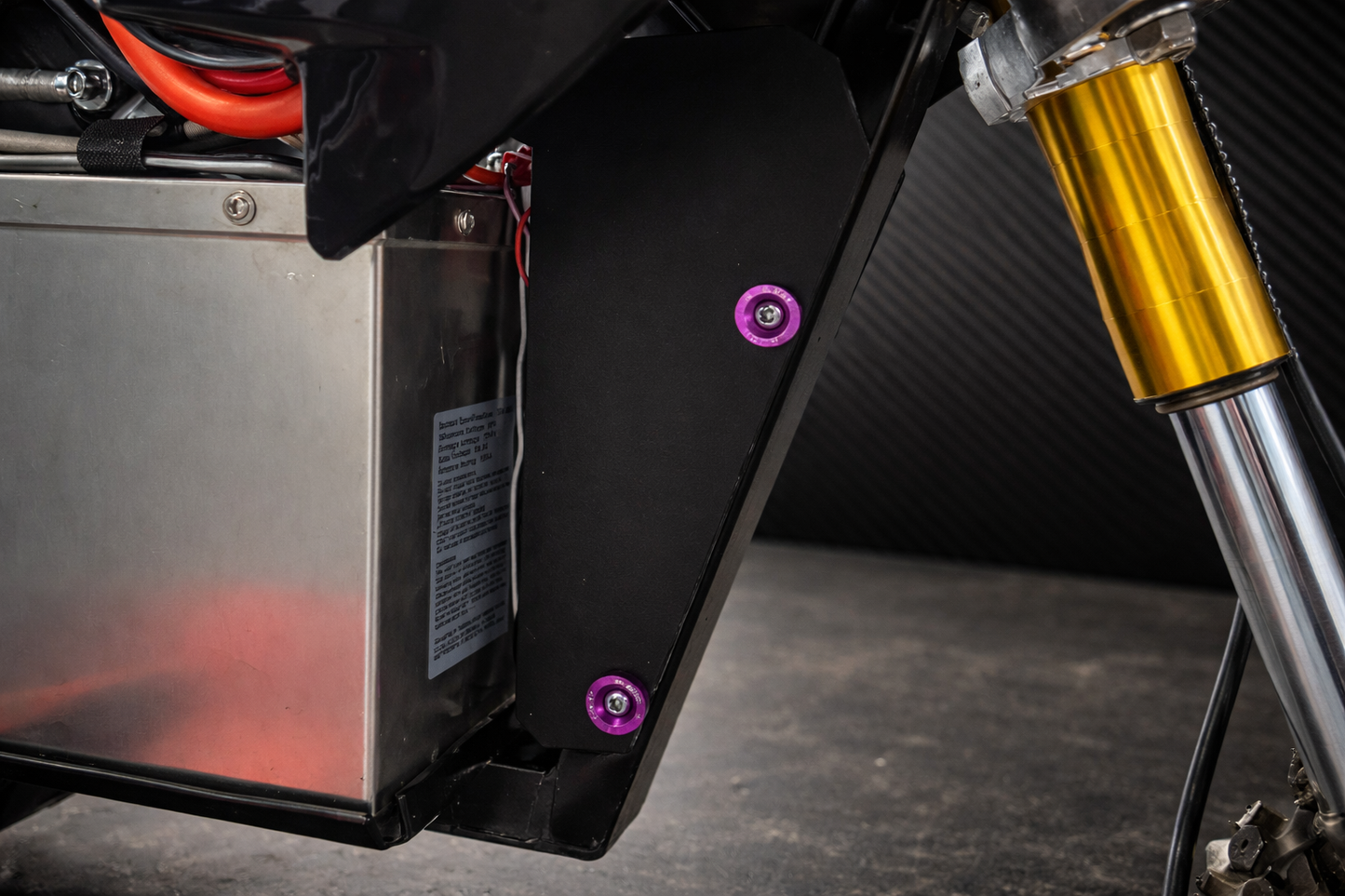 Close-up of a motorcycle's suspension system with a black mxmods and gold shock absorber.