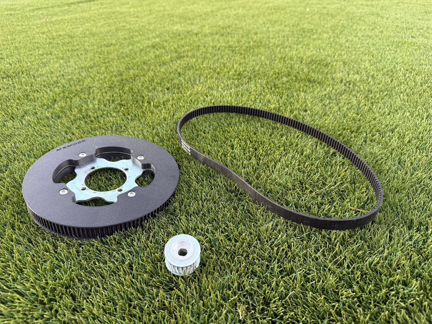 The full Mxmods standars swingarm belt drive kit, on grass background
