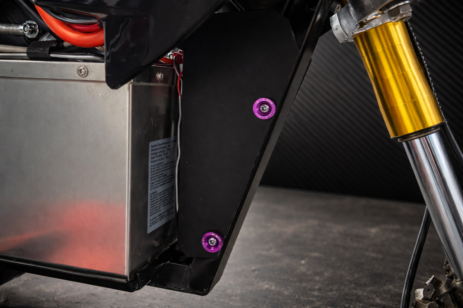 Close-up of a motorcycle's suspension system with a black mxmods and gold shock absorber.