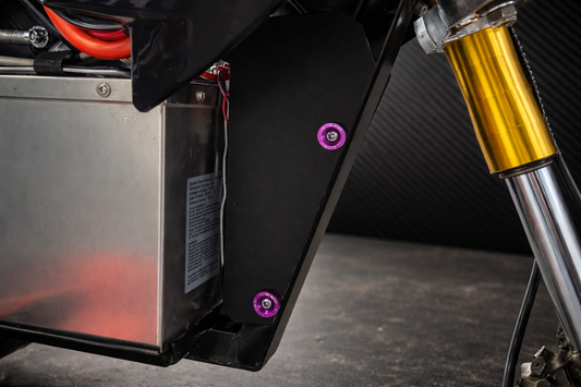 Close-up of a motorcycle's suspension system with a black mxmods and gold shock absorber.